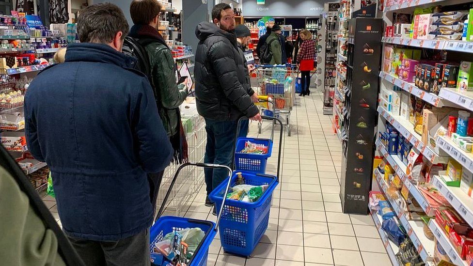 People queue to buy food in Milan as quarantine measures are announced