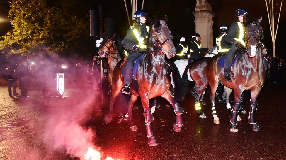 A red flare in front of police horses
