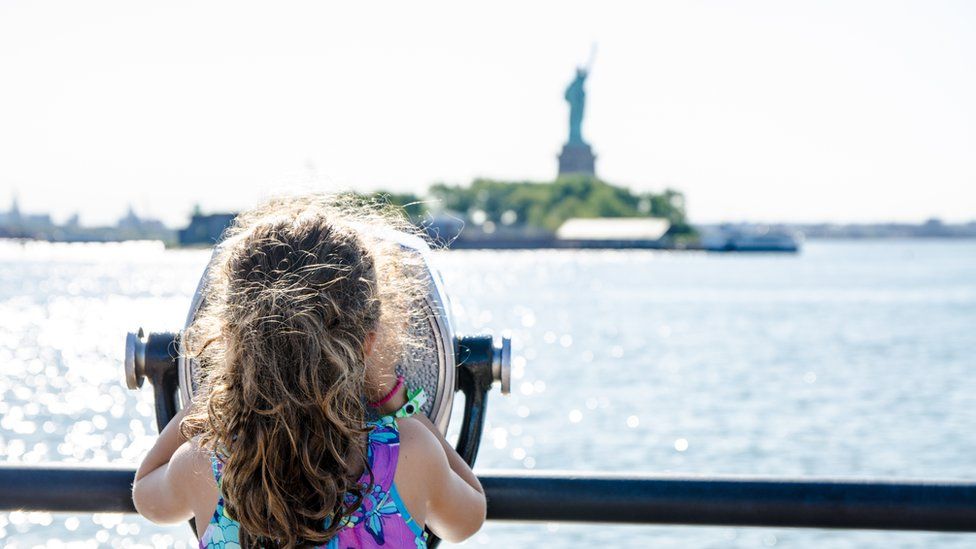 a girl looks at the statue of liberty