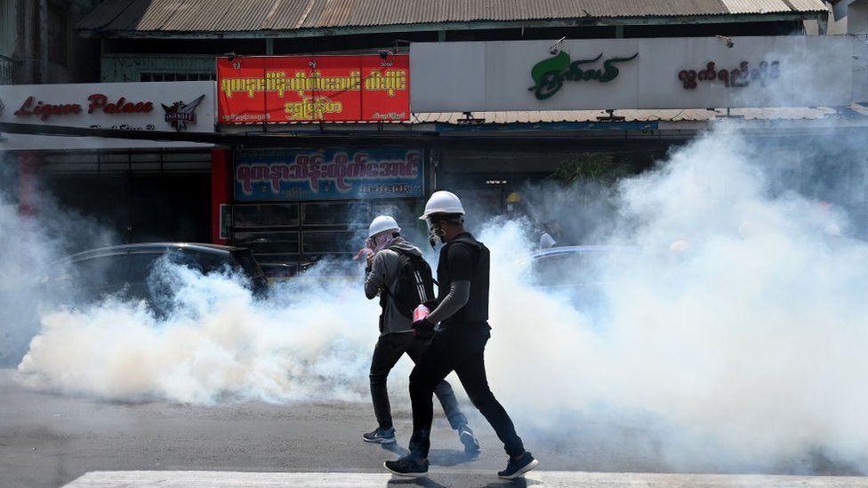 Protesters run after police fired tear gas to disperse them during a demonstration against the military coup in Yangon