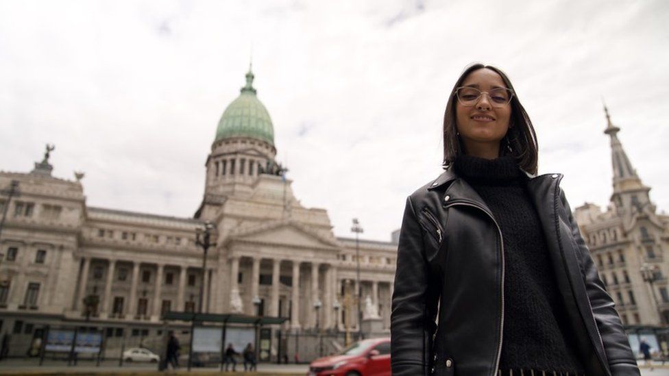 Caro stands in front of buildings