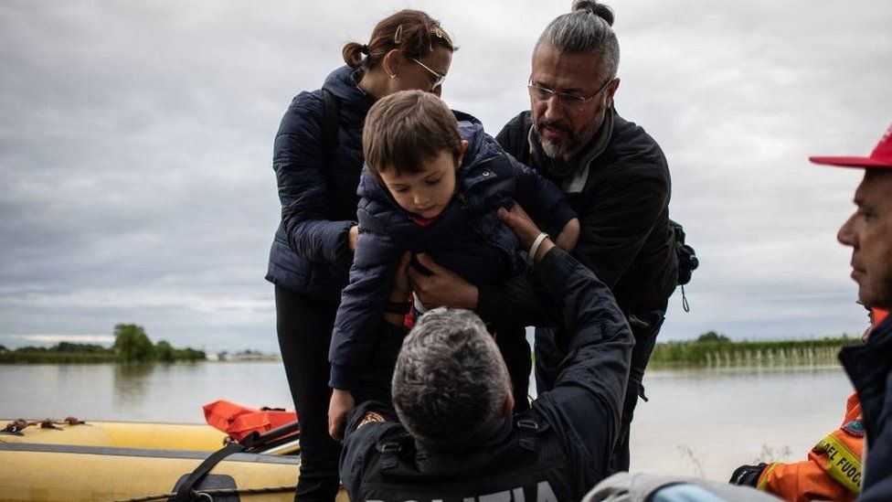 A policeman holds a boy during rescuing operations on May 17, 2023 in Massa Lombarda, a small village about 10 kilometers from Imola,