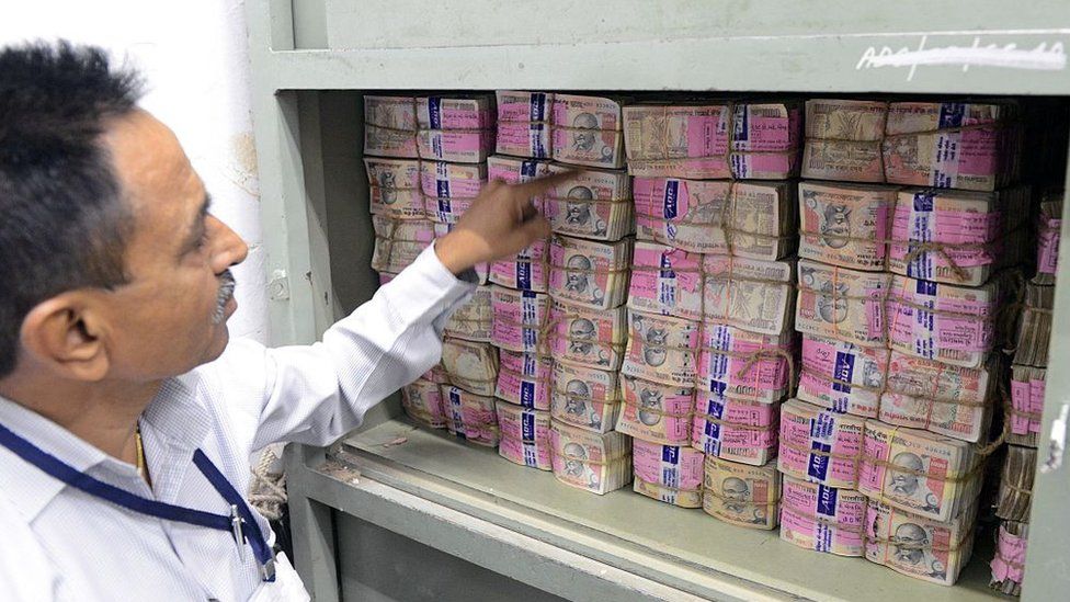 An Indian bank employee looks at deposited old denomination 1000 Rupee currency notes in a bank vault in Ahmedabad