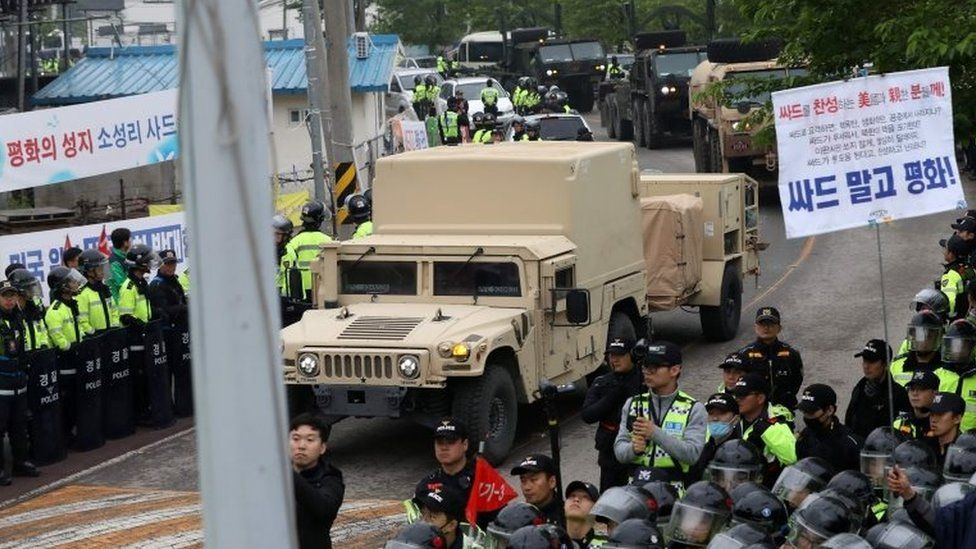 Protesters and police stand by as trailers carrying US THAAD missile defence equipment enter a deployment site in Seongju, early 26 April 2017.
