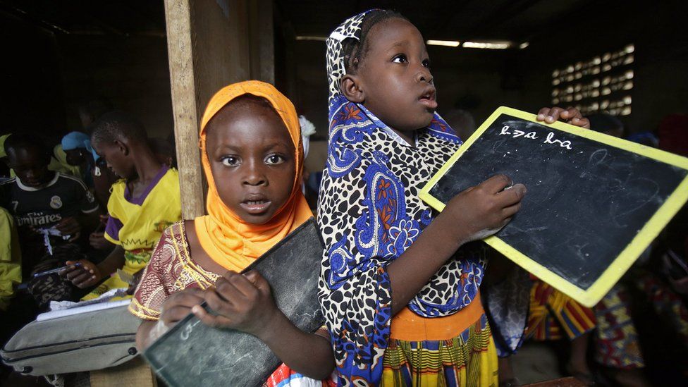 Girls pose with their chalkboards as they attend a class at a school in Abidjan, Ivory Coast, 17 November 2017