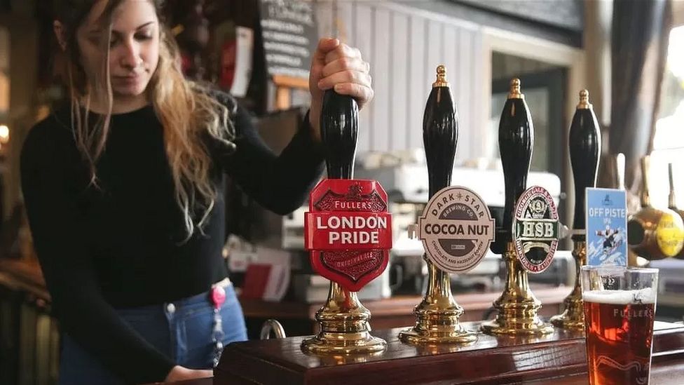 Woman pours a pint in Fullers pub