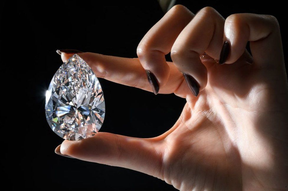 This picture taken on 6 May in Geneva shows "The Rock", which was auctioned on 11 May in Geneva during a "Christies Magnificent Jewels" sale, alongside a yellow diamond, with part of the proceeds going to the International Committee of the Red Cross.