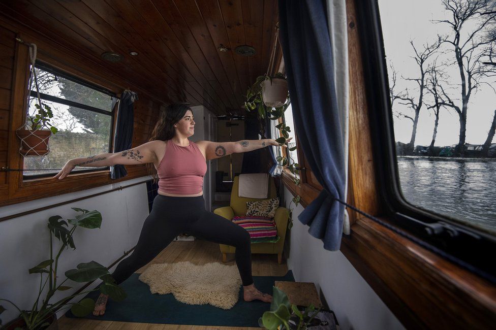 A woman holds a yoga pose in her narrowboat