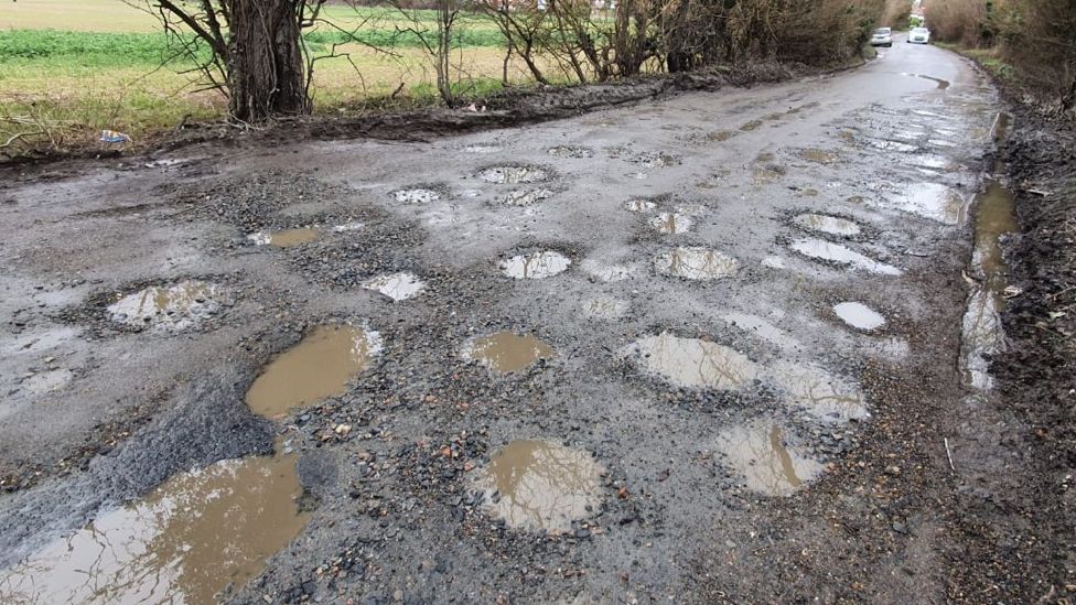 The rural road near Harlow in Essex has many potholes