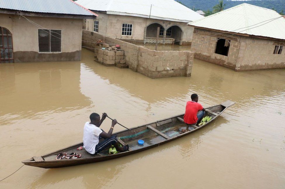 Residents steer a dugout canoe past flooded houses following heavy rain in the Nigerian town of Lokoja, in Kogi State, on September 14, 2018.