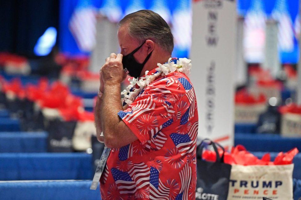 A delegate wears a mask and a Hawaiian flag covered in US flags