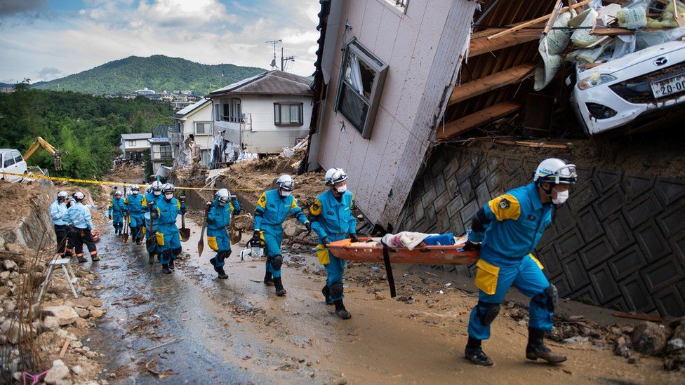 Police arrive to clear debris scattered on a street in a flood hit area in Kumano