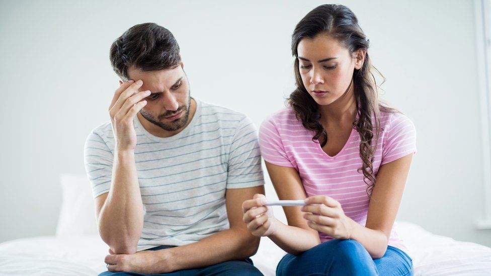 A man and woman looking at a pregnancy test