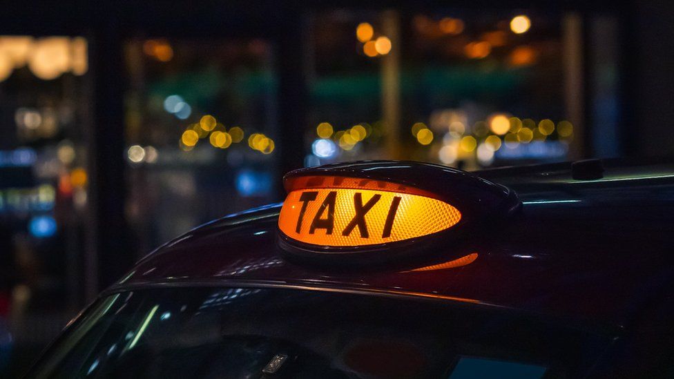 A taxi at night with its rooftop light illuminated