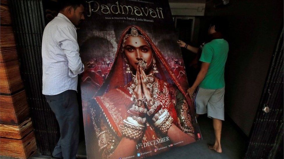 Workers carry a poster advertising upcoming Bollywood film "Padmavati" towards a ticket selling counter in a cinema hall in Kolkata, India, November 28, 2017.