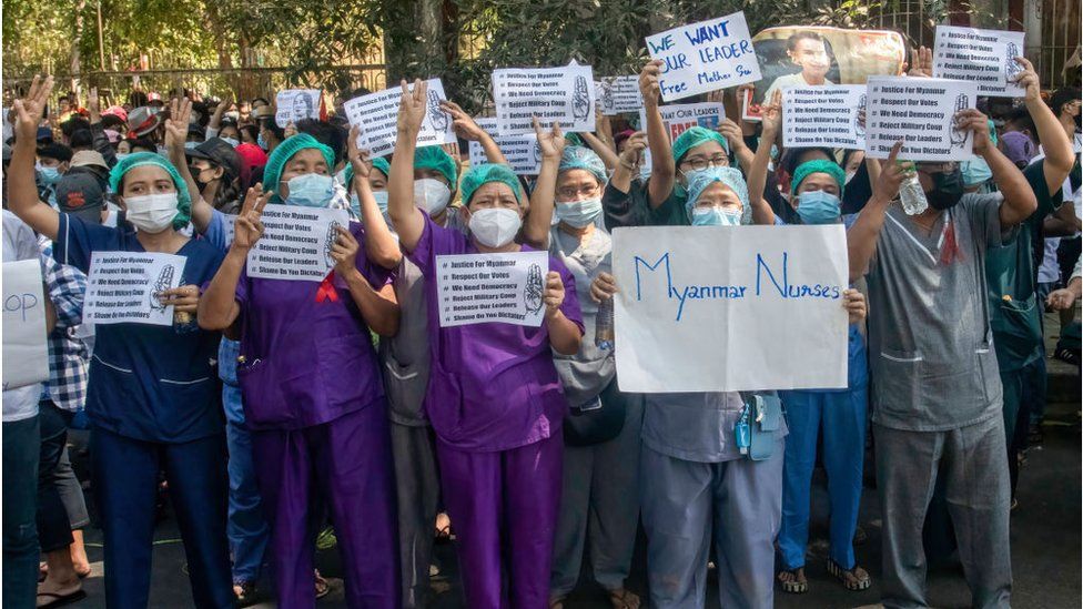 Nurse protesters display signs and raise three finger salutes during the demonstration