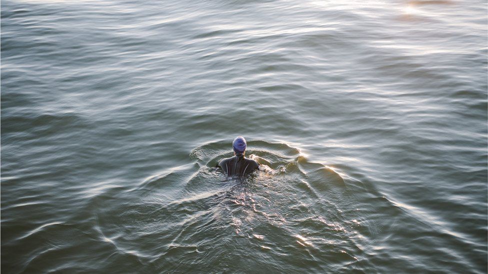 A person swimming in a wetsuit
