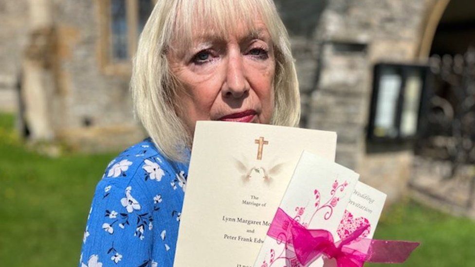 A woman with blonde hair and a blue shirt holding up her wedding day schedule