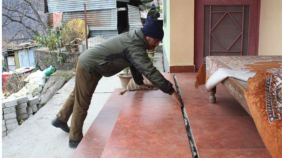 A policeman checks a crack in a house in Joshimath