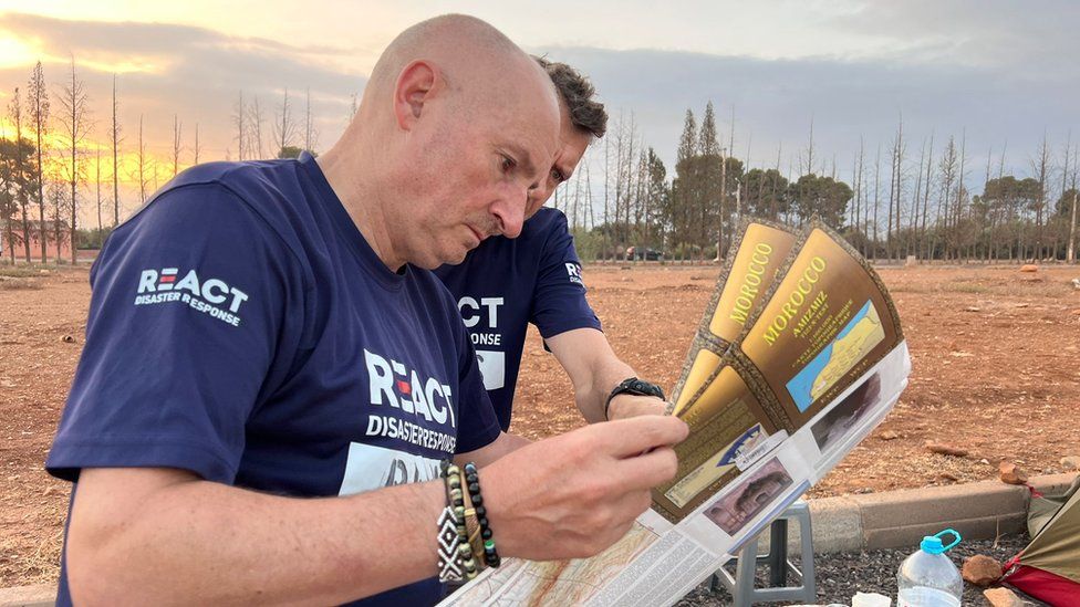 Two men in Re:act t-shirts reading a Morocco map of leaflet