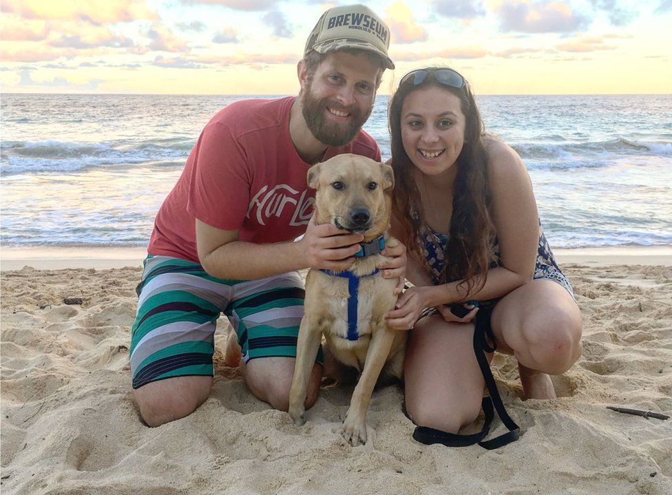 A picture of Emily Young on the beach with her partner and dog