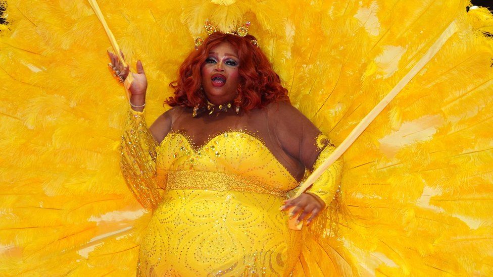 An act in a yellow sequinned costume and feather display