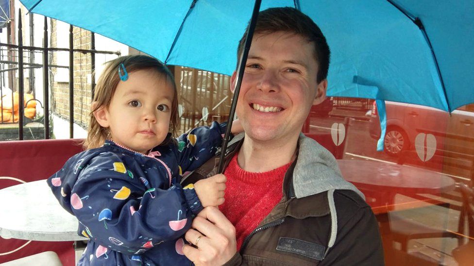 Matthew and his daughter under an umbrella