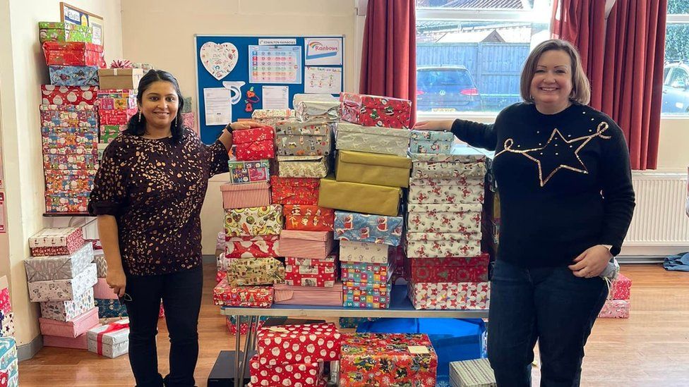 Two volunteers with a pile of Christmas shoeboxes