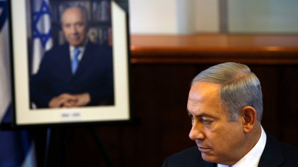Benjamin Netanyahu sits next to a photograph of Shimon Peres in Jerusalem on 28 September 2016
