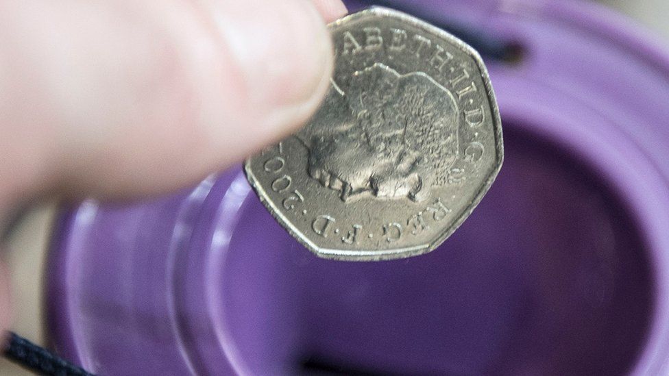 A coin is dropped into a charity collection container