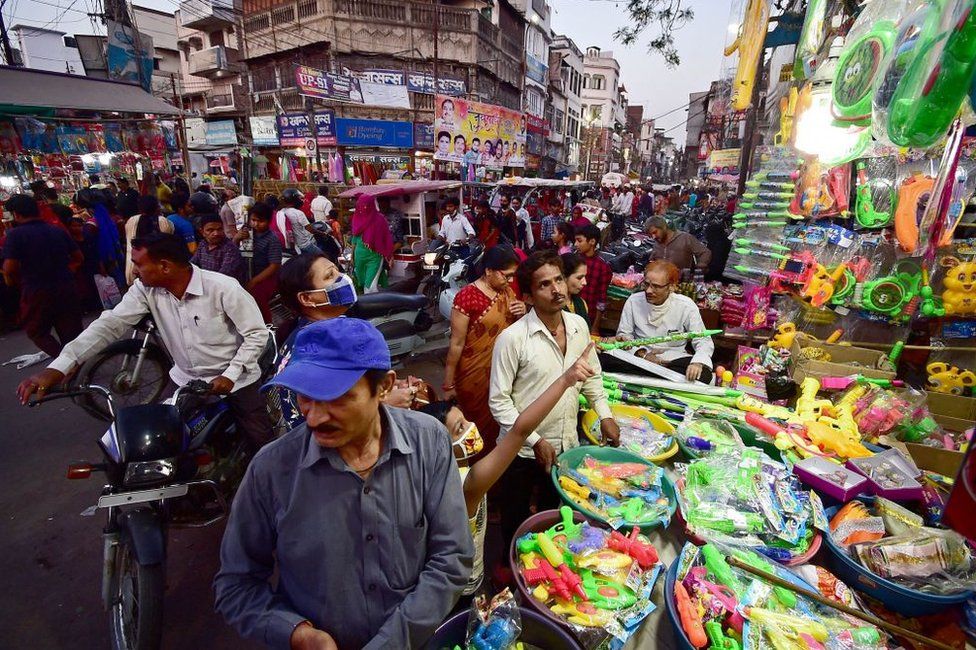 Люди собираются в придорожном магазине, чтобы купить водяные пистолеты для предстоящего празднования Холи, популярного индуистского весеннего фестиваля красок в Аллахабаде 27 марта 2021 года.