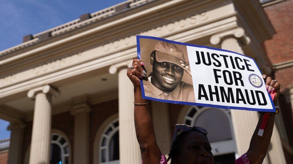 A demonstrator holds a sign in support of Ahmaud Arbery outside the Glynn County Courthouse
