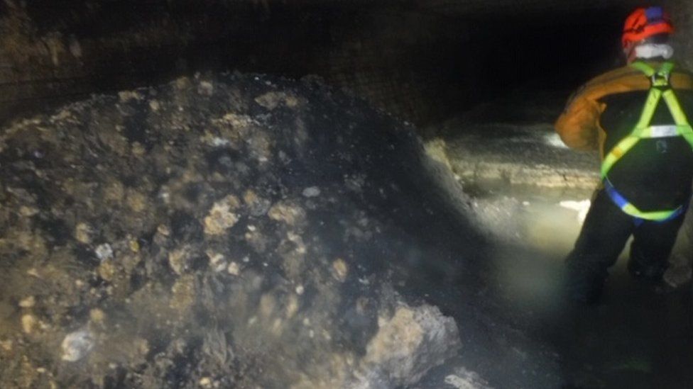 A sewer worker stands next to the "monster" fatberg