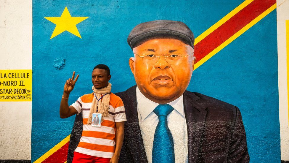A supporter of veteran opposition chief Etienne Tshisekedi poses for a photograph with his portrait front of his residence in Kinshasa, on July 27, 2016. Etienne Tshisekedi,