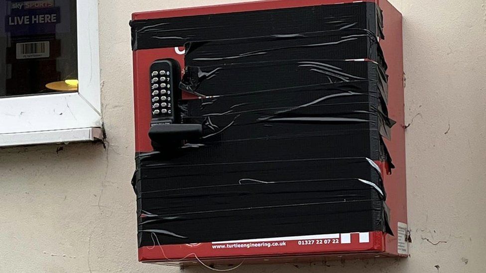 The red box attached to a wall and covered in black tape