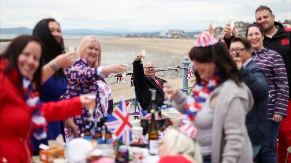 A man raises his glass as people attend the Morecambe Town Council street party amid celebrations
