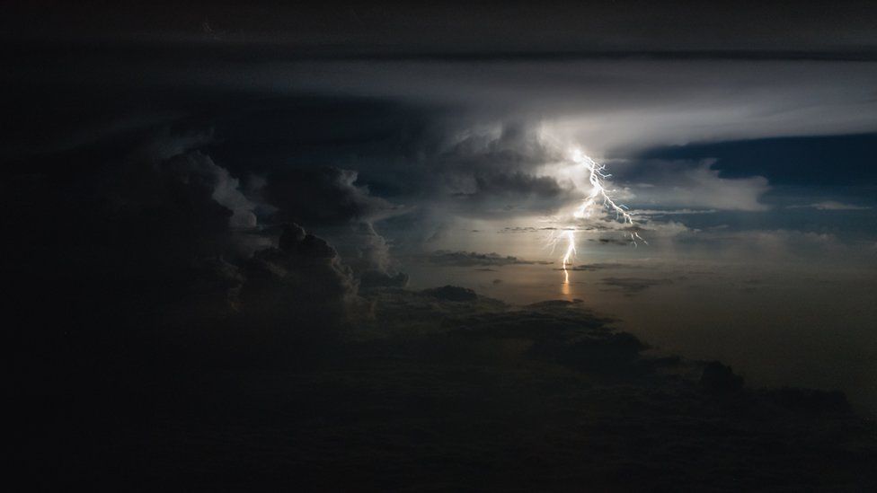 Un rayo ilumina el cielo en la distancia en un marco de nubes oscuras