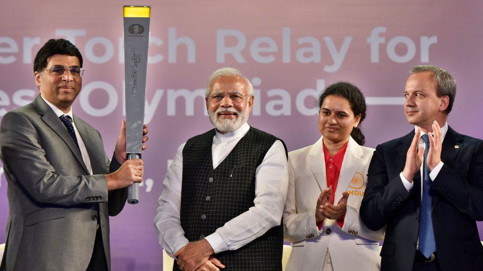 Prime Minister Narendra Modi hands over the torch to Viswanathan Anand during the launch of torch relay for the 44th Chess Olympiad on June 19, 2022 in New Delhi, India. FIDE President Arkady Dvorkovich and Indian chess player Koneru Humpy are also seen.