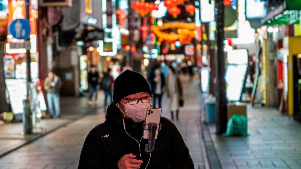 Мужчина идет со своим телефоном по китайскому кварталу Йокогамы