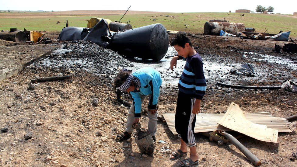 Boys play in the remains of an oil refinery reportedly targeted by the US-led coalition aircraft near northern Syrian town of Tal Abyad (2 October 2014)