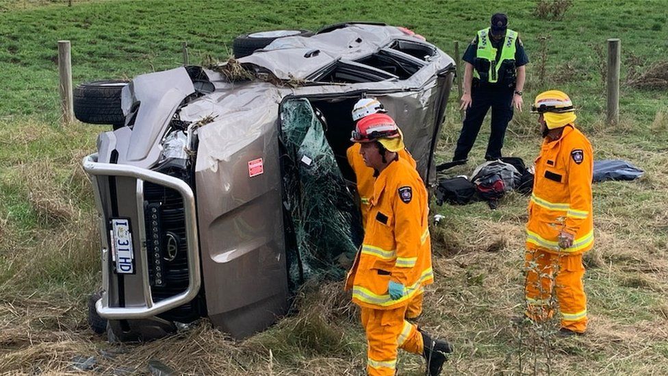 An unmarked police car lies on its side after rolling down an embankment in Tasmania