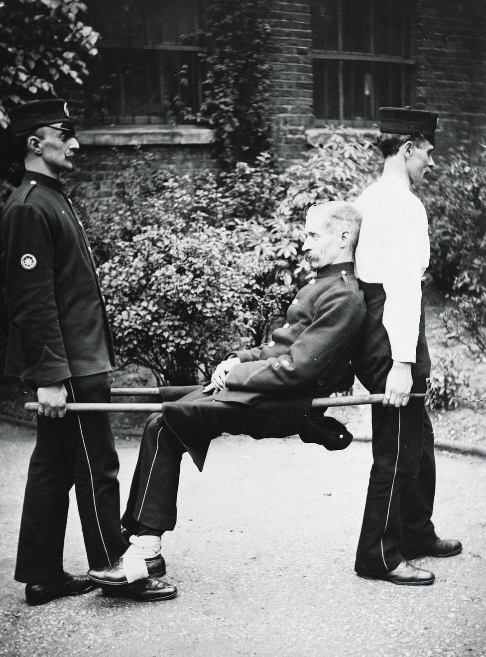 Two men carry another on a stretcher
