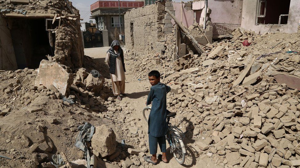 Afghan residents walk near destroyed houses after a Taliban attack in Ghazni on August 16, 2018.