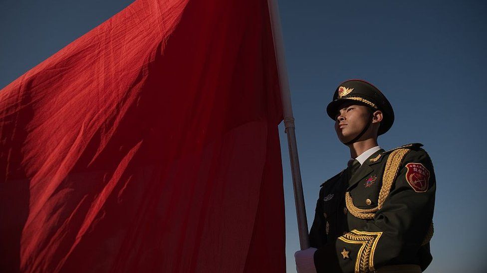 A member of China's military stands with a flag