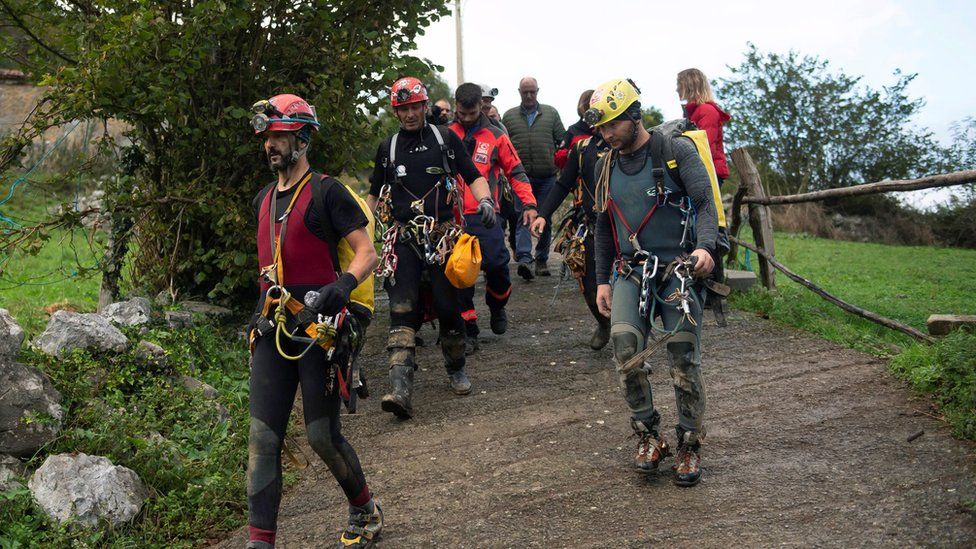 Сотрудники испанских спасательных служб сопровождают четырех пропавших без вести португальцев, которые были спасены после того, как оказались в ловушке в пещере в Арредондо