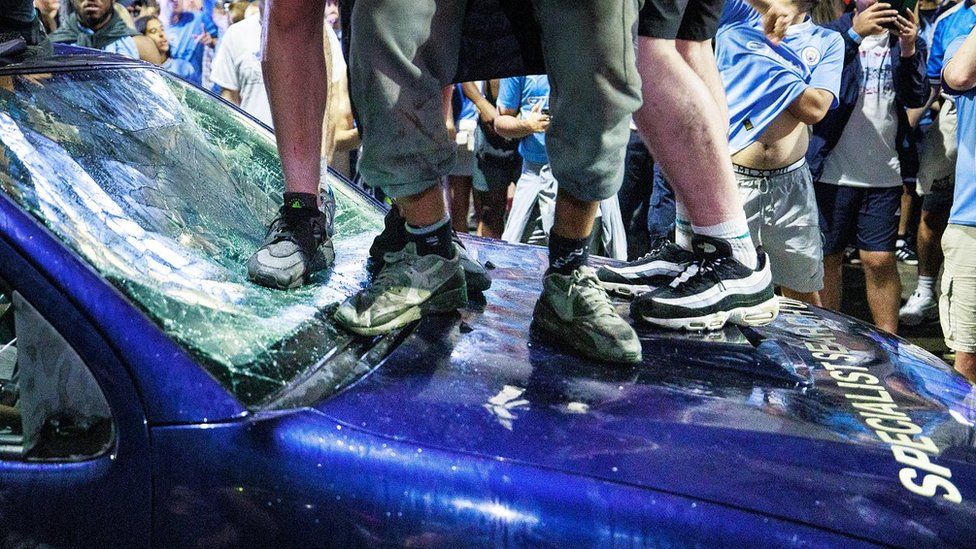 fans on top of police car with smashed window