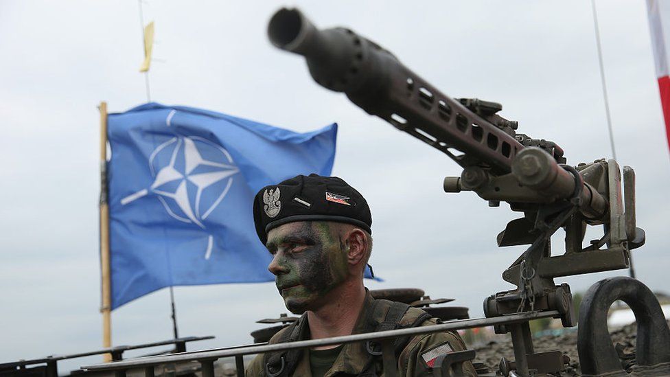 soldier of the Polish Army sits in a tank as a NATO flag flies behind during the NATO Noble Jump military exercises