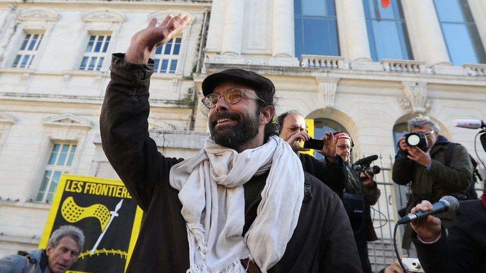 French farmer Cedric Herrou waves as he arrives for his trial at the court of Nice, southeastern France, on January 4, 2017 for allegedly assisting migrants to enter and remain illegally in France