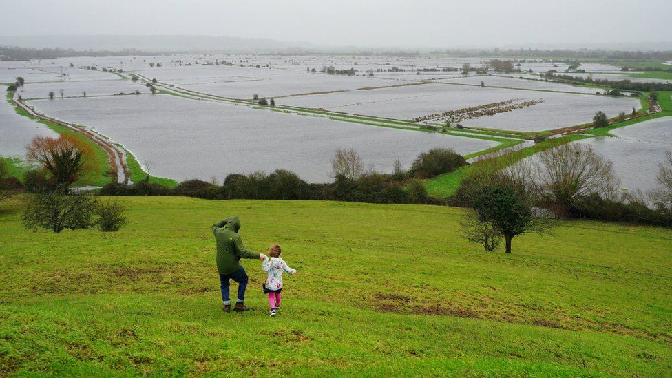 Man and child overlook a flooded river