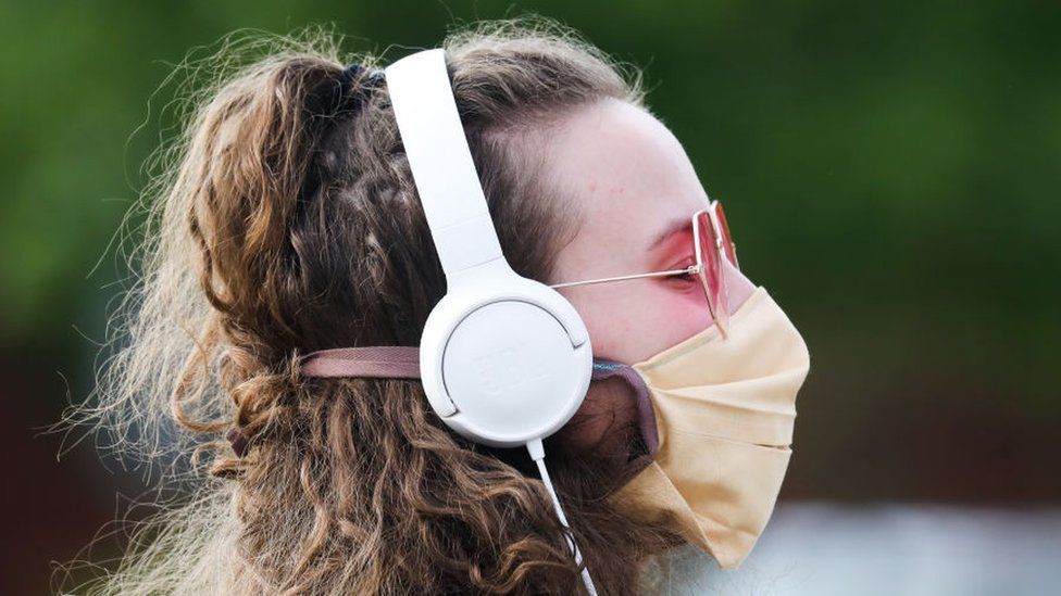 Woman wearing headphones and a mask